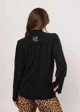 Camisa negra de cuello redondo con frunces y mangas largas con puños abiertos.