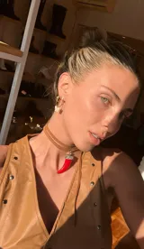 Gargantilla de cuero tostado con dije colgante en forma de cuerno rojo brillante y capuchón plateado con detalles grabados.
