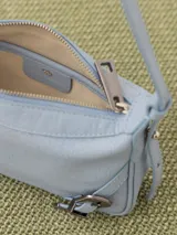 Mini cartera bandolera de cuero vacuno flor color negro con interior al tono. La correa regulable combina cuero y pelo, y lleva hebillas metálicas personalizadas.