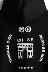 Canguro negro de corte holgado con capucha, bolsillo frontal tipo canguro y puños acanalados. Presenta un estampado gráfico minimalista en color blanco en el pecho que incluye letras, un ícono arquitectónico y estrellas.