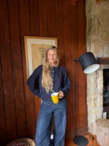 Saco tejido de punto con diseño de ochos y trenzas, color azul marino. Presenta cierre frontal con botones en contraste de color turquesa y un delicado bordado a mano en el pecho.