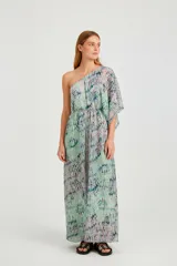 Vestido largo de diseño asimétrico con un solo hombro, confeccionado en tela fluida con estampado abstracto en tonos verdes y azulados. Presenta una manga tipo capa y corte holgado con elástico en la cintura.