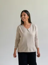 Sweater de punto fino en color beige, con escote en V y mangas largas con puños ajustados.