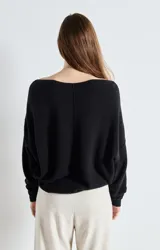 Sweater de punto de corte amplio y holgado, con cuello barco y mangas largas. Presenta una textura esponjosa y un diseño minimalista.