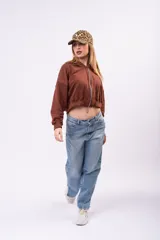 Campera cropped de color marrón con cierre frontal completo, capucha y mangas largas. Presenta un pequeño bordado blanco en el pecho y un diseño holgado.