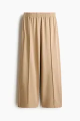 Pantalón de punto color beige con cintura elástica fruncida, piernas amplias, pliegues delanteros y ribetes laterales en color blanco.