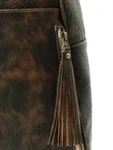 Mochila Hush Puppies modelo Saba de cuero color marrón con efecto avejentado, asa superior y tiras de flecos decorativos en los cierres laterales.