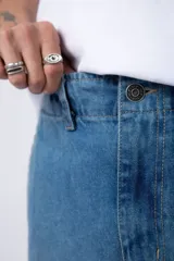 Pantalón jean cargo de corte oversize y tiro medio, con bolsillos laterales tipo cargo y costuras reforzadas en las rodillas.