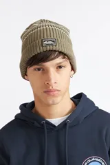 Gorro de lana Quiksilver tipo beanie en color verde militar, con diseño acanalado, franjas horizontales en la parte superior y parche con logo de la marca en el frente.