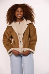 Campera tipo gamulán de gamuza color marrón con interior y solapas de corderito sintético color beige. Presenta cierre frontal con botones, mangas largas y corte holgado.