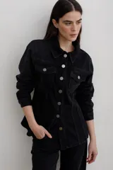 Chaqueta de denim negro con corte entallado en la cintura, cuello clásico, cierre frontal con botones metálicos y bolsillos frontales con solapa.