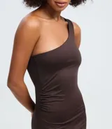 Vestido midi ajustado de color marrón, con diseño de un solo hombro y escote asimétrico. Presenta un sutil fruncido lateral que realza la silueta y una abertura lateral para mayor movilidad.