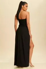 Vestido largo negro de corte ajustado, con escote strapless decorado con apliques de cristales y una abertura lateral profunda en la pierna con detalle de cristales en el borde.