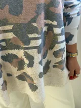 Sweater de punto con escote en V y mangas largas, de diseño holgado. Presenta un estampado animal print abstracto en tonos chocolate y detalles metalizados en color dorado sobre una base color crema.
