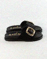 Sandalias de cuero color negro, de diseño plano con una tira ancha en el empeine y una hebilla metálica dorada grande como detalle.