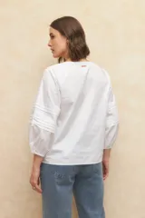 Blusa blanca de algodón bordada, de manga larga con cuello mao y mangas abullonadas con elástico en los puños.