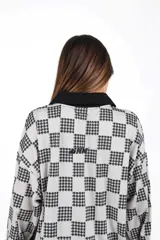 Casaca unisex de manga larga, con cuello tejido negro y estampado a cuadros en blanco crudo y negro.
