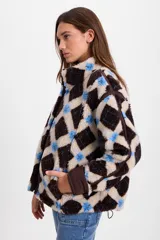 Campera de corderito sintético con diseño a cuadros en tonos marrones y negros. Presenta cuello alto, cierre frontal completo y detalles de paneles en color marrón liso. El diseño es de silueta holgada, largo tipo crop y cuenta con un cordón elástico ajustable en el ruedo.