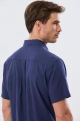 Camisa de manga corta confeccionada en mezcla de lino y algodón, color beige, con cuello camisero abotonado, bolsillo frontal en el pecho y cierre de botones.