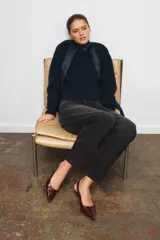 Zapato de tacón tipo destalonado confeccionado en piel con acabado brillante. Presenta diseño de punta fina, pespuntes decorativos en el empeine y tira trasera con elástico lateral. Incluye tacón kitten fino.