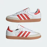 Championes Adidas modelo Samba OG, fabricados en cuero blanco con las icónicas tres tiras y detalles en rojo solar, puntera de nobuk gris claro y suela de goma marrón.