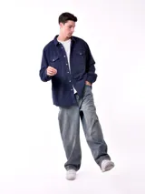 Sobrecamisa de hombre color azul marino, confeccionada en tejido de pana con textura acanalada. Presenta cuello camisero, cierre frontal con botones blancos y dos bolsillos de parche con solapa en el pecho.