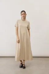 Vestido midi color beige de manga corta y cuello redondo, con diseño holgado y caída fluida.