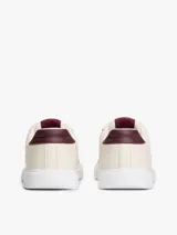 Zapatillas Tommy Hilfiger de diseño bajo color beige, con detalles en tono bordó en el talón y la lengüeta, suela blanca y logo distintivo de la marca en el lateral.