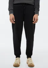 Pantalón tipo babucha de color azul oscuro, confeccionado con interior de felpa. Presenta cintura elástica con cordón de ajuste y puños acanalados en los tobillos.