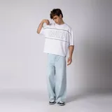 Remera gris oscuro de corte boxy, manga corta amplia, con cuello redondo y diseño gráfico frontal con la palabra "CONCEPTO" delineada en blanco dentro de un panel horizontal.