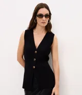 Chaleco largo de tricot color negro, con escote en V profundo, cierre frontal con botones metálicos y bolsillos delanteros embutidos.
