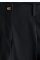 Pantalón sastrero de corte holgado color negro, con cintura clásica, cierre con botón y trabillas para cinturón. Cuenta con piernas rectas, pinzas, bolsillos al bies y raya marcada adelante y atrás.
