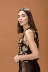 Chaleco de terciopelo marrón con escote en V profundo y bordados florales en hilo color crema. Presenta un diseño sin mangas con terminaciones bordadas en los bordes.