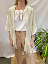 Ruana tejida de textura suave y liviana, color dorado, con flecos en los extremos.