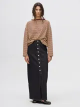 Pollera midi de denim color negro, de tiro medio y corte recto. Presenta un cierre frontal con botones metálicos a la vista y un tajo central en el ruedo con terminación desflecada.