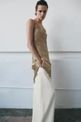 Vestido midi de satén con escote asimétrico y tirantes finos. Presenta una aplicación de encaje a tono en el escote y un bajo asimétrico.