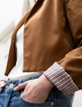 Blazer crop color marrón, marca Dictionary. Cuello con solapa, manga larga y forro interno estampado a rayas.