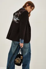 Saco sastre de color negro con corte clásico y solapas. Presenta un bordado artístico en la espalda con motivos de montañas, nubes y flores en tonos suaves.