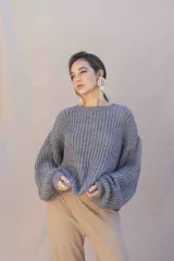 Buzo de tejido grueso en color azul marino, con corte relajado, cuello redondo y mangas largas amplias. Presenta una etiqueta con el logo de la marca en la parte superior de la espalda.