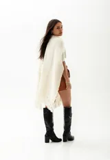 Ruana negra de tejido de punto grueso con flecos en el borde inferior.