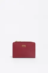 Billetera compacta de estructura blanda en color turquesa, con cierre de cremallera superior y logo metálico dorado en el frente.