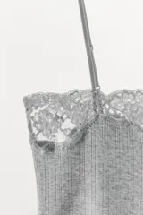Top de punto fino con textura acanalada, escote recto y tirantes finos ajustables. Presenta una delicada aplicación de encaje a tono en el borde superior.