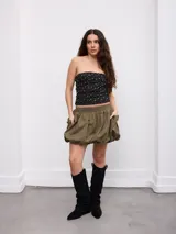 Falda corta tipo globo en color verde militar, con estilo cargo, cintura elástica fruncida y bolsillos laterales amplios.