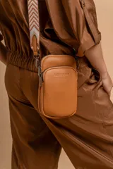 Phonebag de diseño compacto y moderno, color plateado, con cierre frontal y correa ajustable y desmontable con diseño geométrico. Cuenta con logo grabado en el frente.