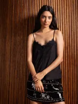 Top de breteles finos estilo camisola, confeccionado en material símil gamuza color negro, con detalle de encaje en el escote y costura vertical frontal.