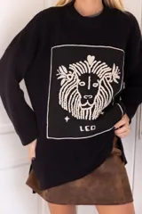 Sweater negro de punto con cuello redondo y calce oversize. Presenta un aplique cuadrado con el dibujo de un león y la palabra 'Leo' bordados en color crudo.