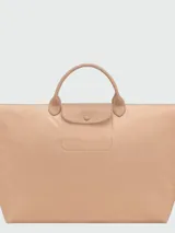 Bolso de mano tipo tote de la línea Le Pliage One de Longchamp, en color bordó. Presenta un diseño minimalista con cierre de cremallera superior, solapa con botón a presión y asas cortas de cuero.