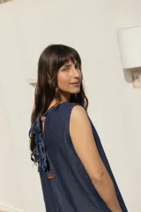 Vestido corto de denim liviano, de silueta evasé y calce relajado, sin mangas, con escote redondo y detalle de lazos en la espalda.
