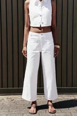 Pantalón blanco de jean con bordados calados en los laterales, de tiro medio y pierna ancha.