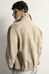 Cazadora relaxed fit de piel y ante color beige, con cuello solapa, manga larga con puño, bolsillos delanteros con solapa y cierre frontal oculto con cremallera y botones a presión.